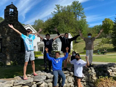 A group of kids posing on a stone wall at the Trinity Retreat Center