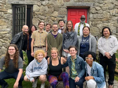 A diverse group of young adults smile while posing in front of the Chapel at Trinity Retreat Center