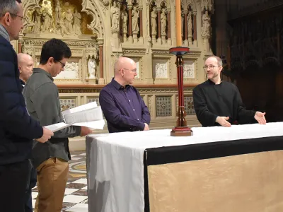 Dane Miller stands behind the Trinity Church altar, speaking and providing a demonstration to new liturgical volunteers