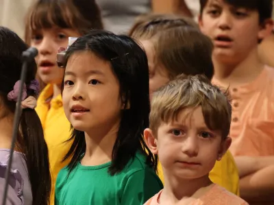 Trinity Youth Chorus singers in orange and green shirts.