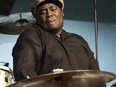 Johnathan Blake playing a cymbal on a drum set.