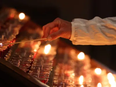 A person reaching to light a candle in Trinity Church