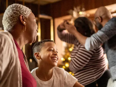 Families dancing in a living room with a Christmas tree