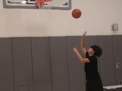 Child throws basketball to hoop in the Trinity Gym.