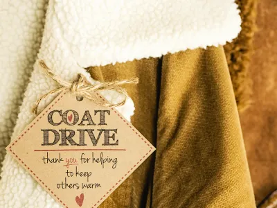 Image of winter coats, with a tag reading: COAT DRIVE - thank you for helping to keep others warm