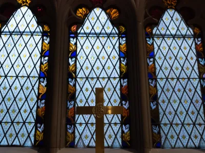 Soft blue lights fills stained-glass windows in Trinity Church with a gold cross in the foreground