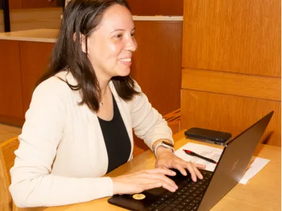 Carmen smiles while using a laptop.