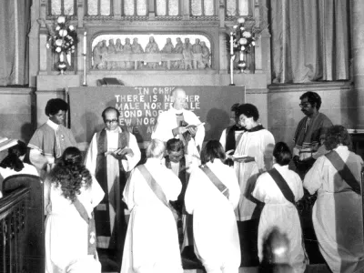 Women kneel at an altar during an ordination service