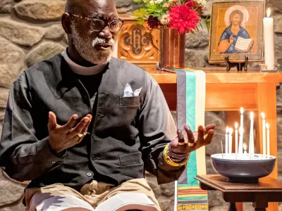 Father Mark Bozzuti-Jones speaks to the camera during a Candlelight Compline service in the Stone Chapel at Trinity Retreat Center.