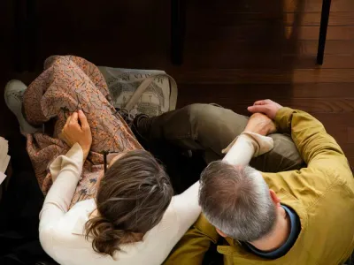 View of the top of the heads of a man and a woman seated with their arms around one another. 