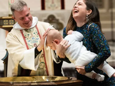 Father Bird joyfully baptizes a baby, mom laughs.