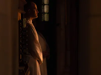 A sacristan stands in the warm glow of light inside Trinity Church