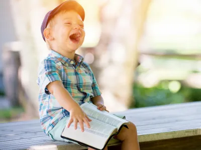 A laughing kid with a book