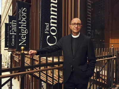 The Rev. Phil Jackson, Trinity’s rector, stands on a pedestrian bridge in front of Trinity Commons in Lower Manhattan