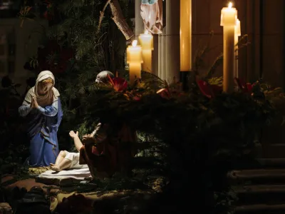 The figurine of Jesus's birth next to candles.