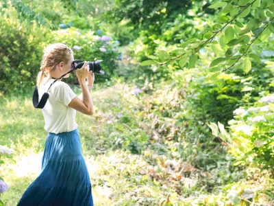 A girl takes a pic with her camera in the woods