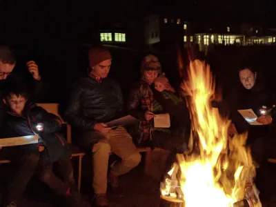 A group of families gather at the bonfire.