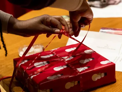 A person wraps a gift with ribbon.
