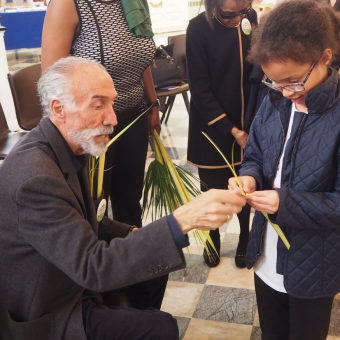 A man shows a little girl how to make a palm cross