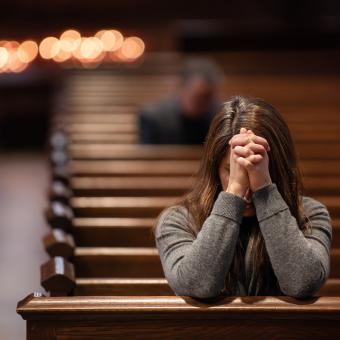 A person prays in a pew in Trinity Church