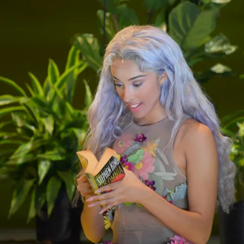 Persephone reads a book in Julian Wachner's REV 23 with a green background