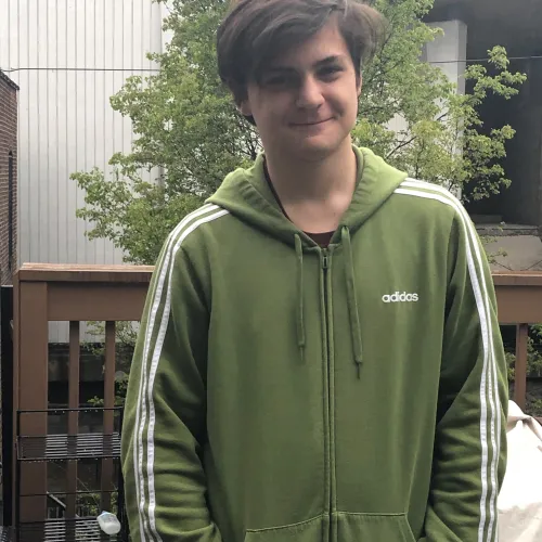 Luca Zubieta, wearing a green sweatshirt, smiles with a closed mouth and looks directly into camera. 