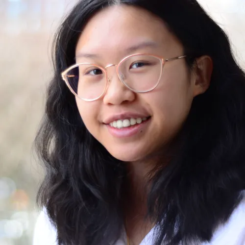 Victoria Lee smiles and looks directly into camera while wearing glasses.