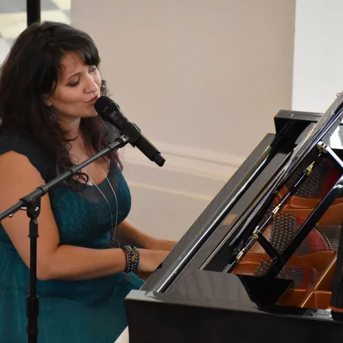 Woman sings while playing the piano as part of a Sunday Afternoon concert at St. Paul's Chapel