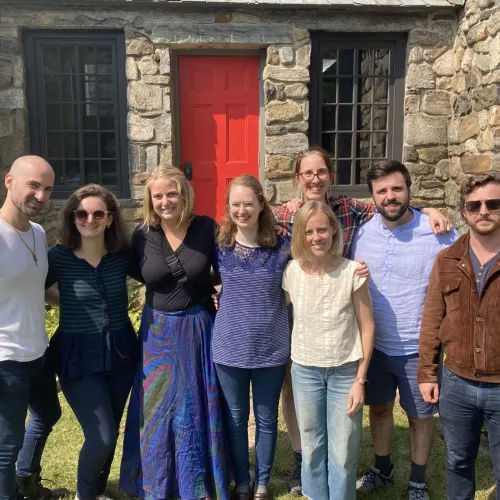 A group of young adults gathers in front of the stone chapel at Trinity Retreat Center