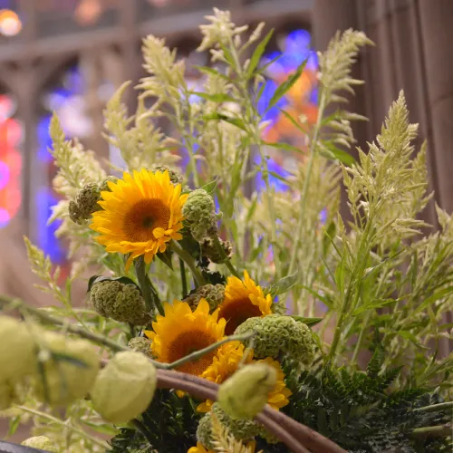 Sunflowers arranged in front of Trinity's stained glass window.