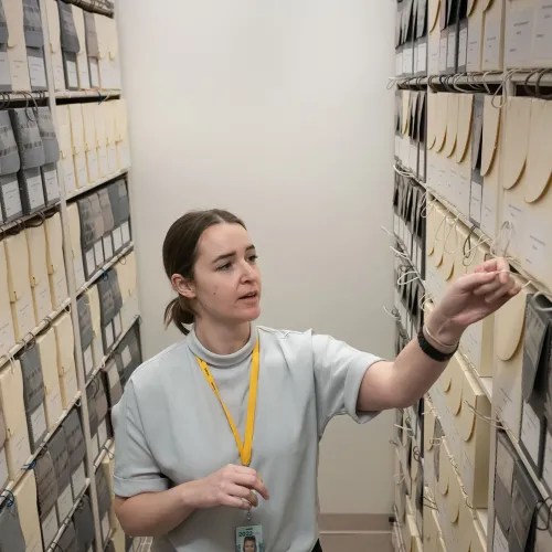 Woman pulls an archival box off of full storage shelves