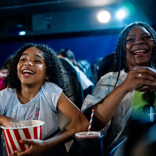 Mother and daughter duo laugh at the movie theater.