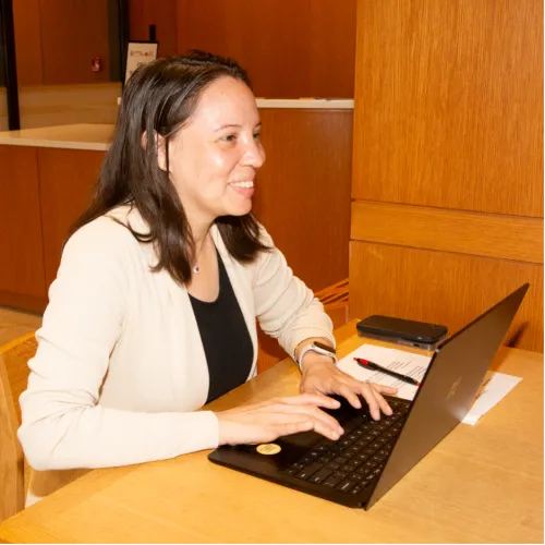 Carmen smiles while using a laptop.