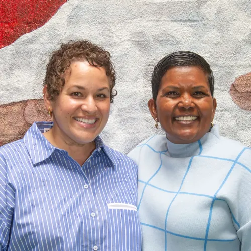 Lorelei and Vidia smile in front of a mural on the Lower East Side