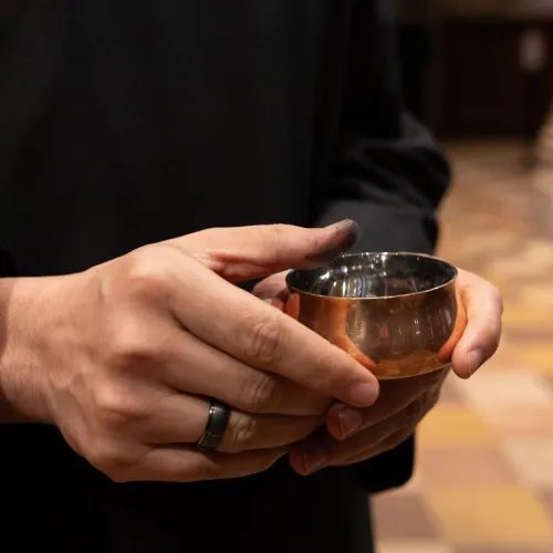 A close-up of a person holding a small container of ashes in Trinity Church on Ash Wednesday